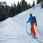 A skier descending a fresh powder run at Sunshine Village, with snow-laden pines and mountains behind